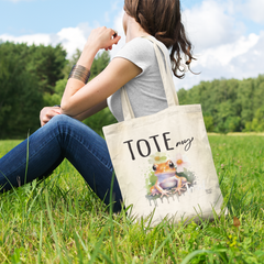 tote-bag-mockup-of-a-woman-sitting-at-a-green-meadow-23-el (1)